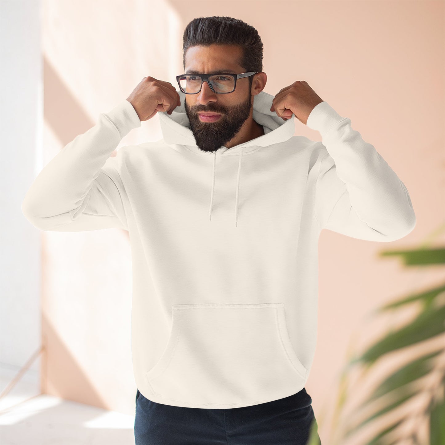 Man wearing a white hoodie with a logo, standing indoors against a light background.