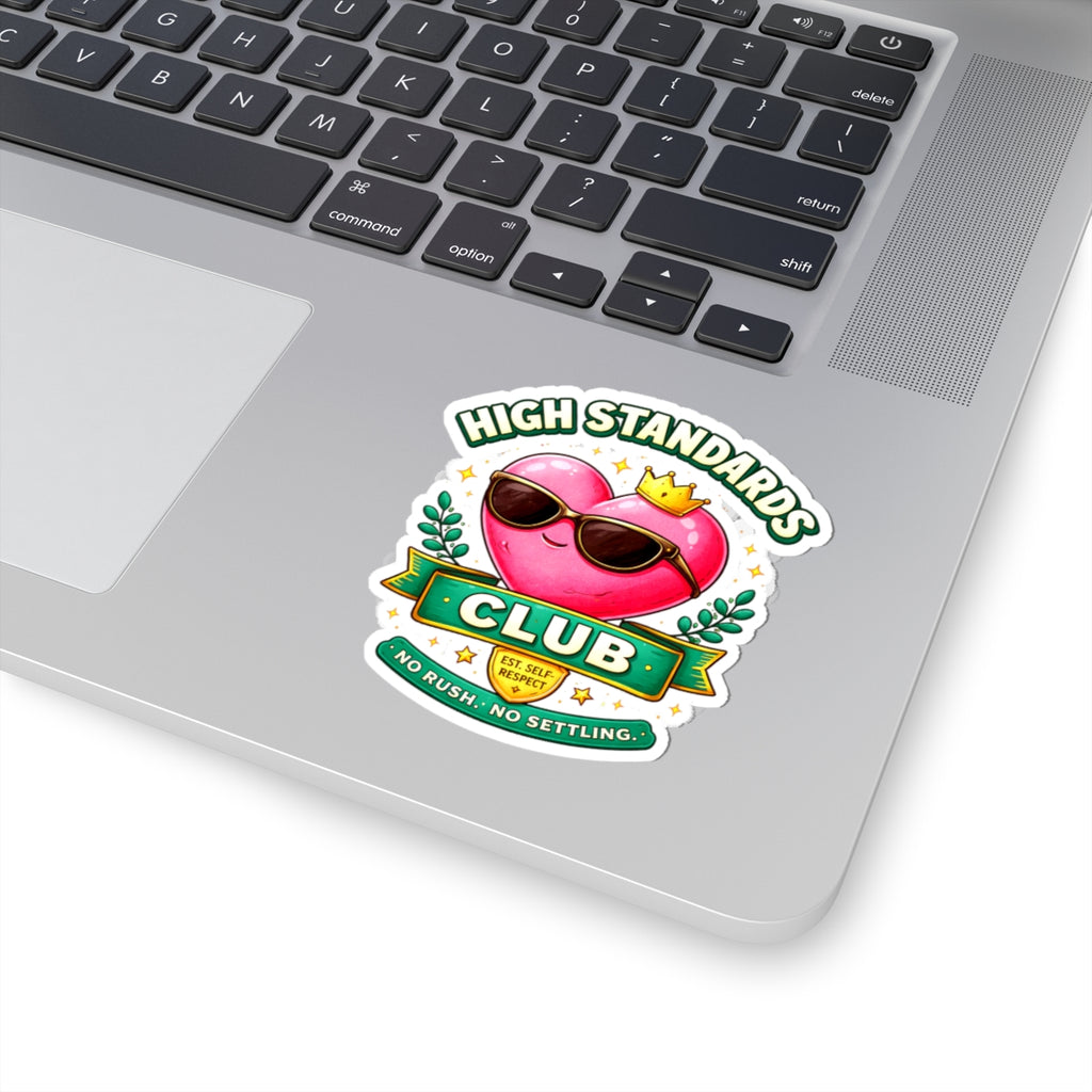 Laptop with a 'High Standards Club' sticker featuring a pink flamingo wearing sunglasses and a crown.