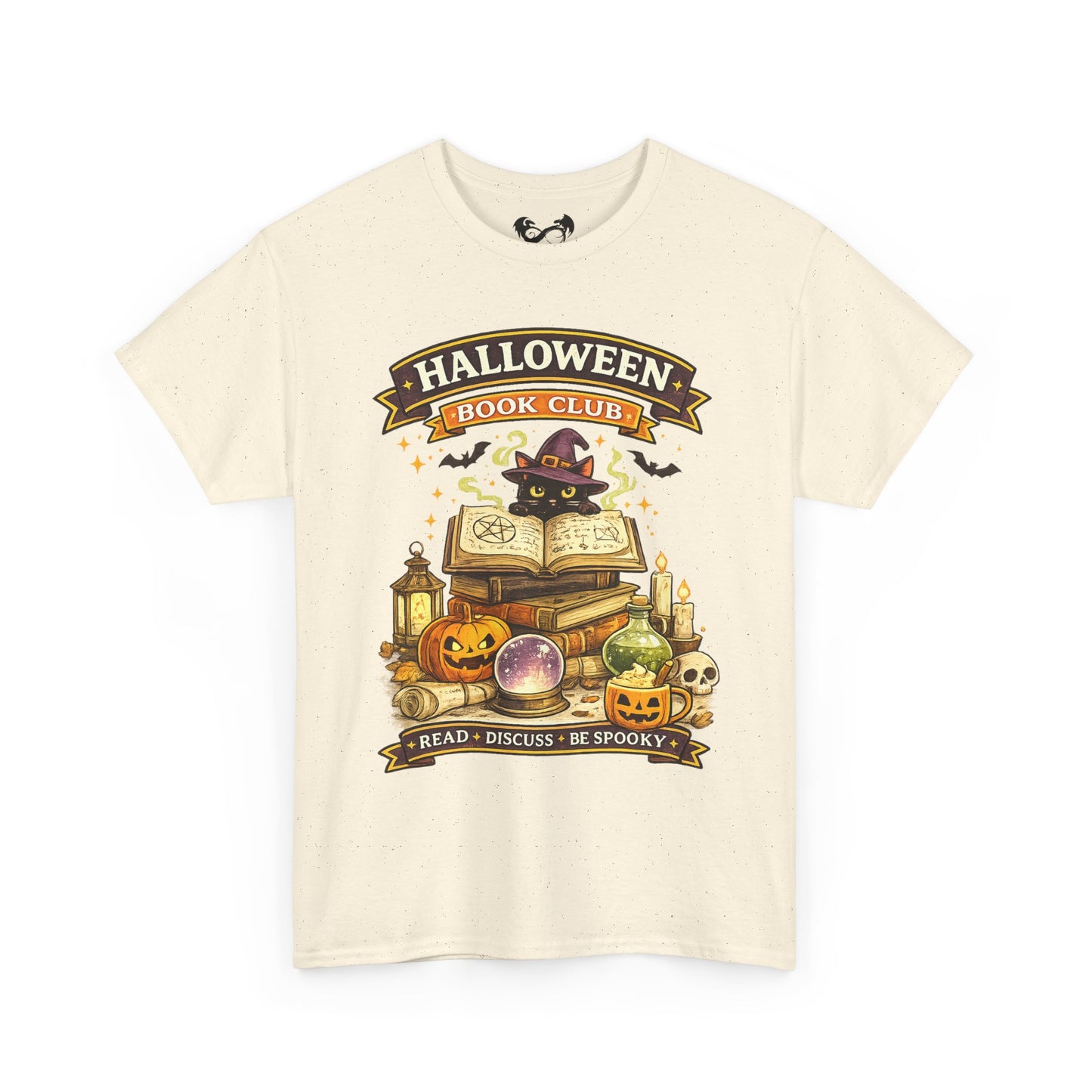 An off-white short-sleeve t-shirt with a graphic print on the front. The graphic features a witch cat wearing a purple hat next to an open book, surrounded by pumpkins, a cauldron, candles, and banners that read 'HALLOWEEN BOOK CLUB' and 'READ • DISCUSS • BE SPOOKY'.