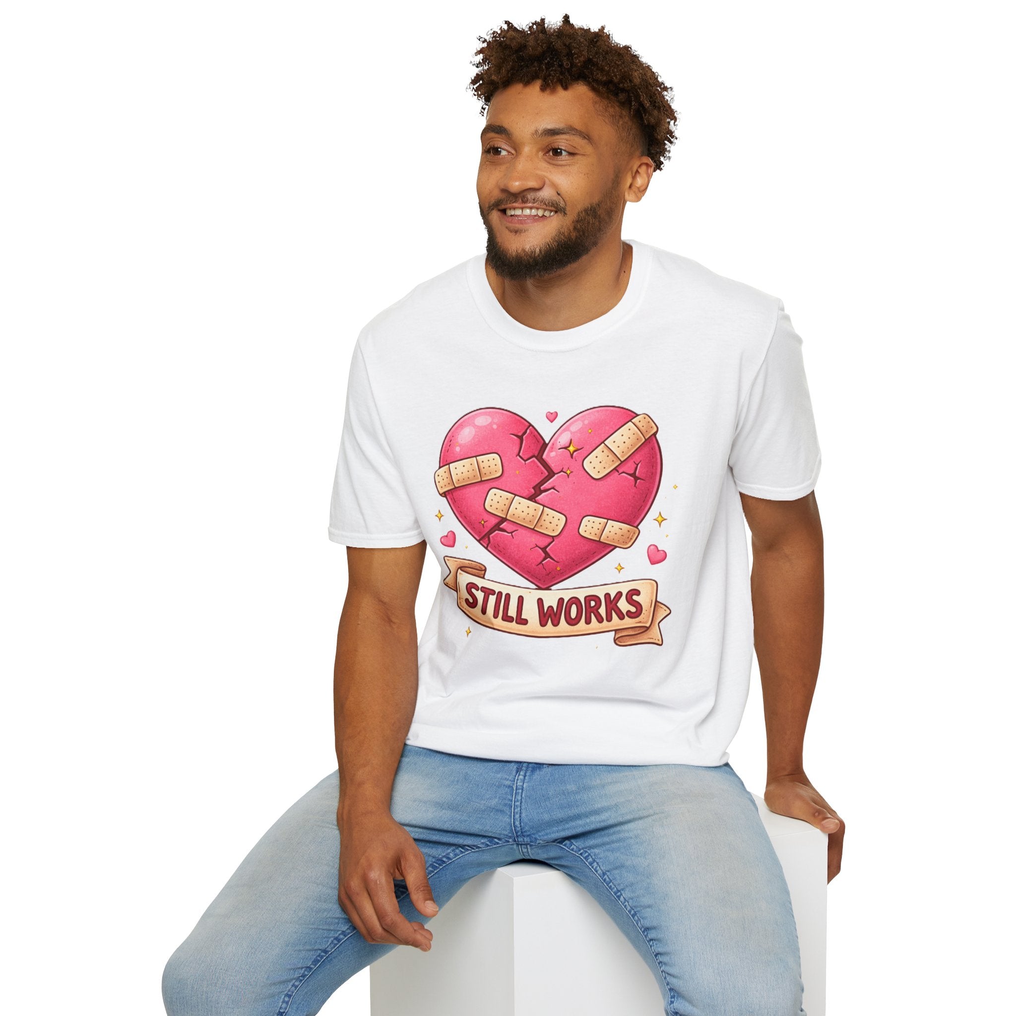Man wearing a white t-shirt with a heart design and text, sitting on a white stool against a white background.