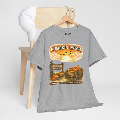 A heather gray graphic t-shirt hanging on a wooden hanger from a light wood chair. The shirt features a fall-themed 'Pumpkin Patch' graphic with pumpkins, a wagon, and a sunset.