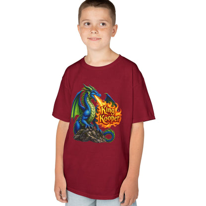 A child wearing a short-sleeve crewneck t-shirt in maroon with a colorful graphic of a blue and green dragon breathing fire, with the text 'King Kooper' in yellow/orange flames. The child is also wearing light blue jeans, set against a plain white background.