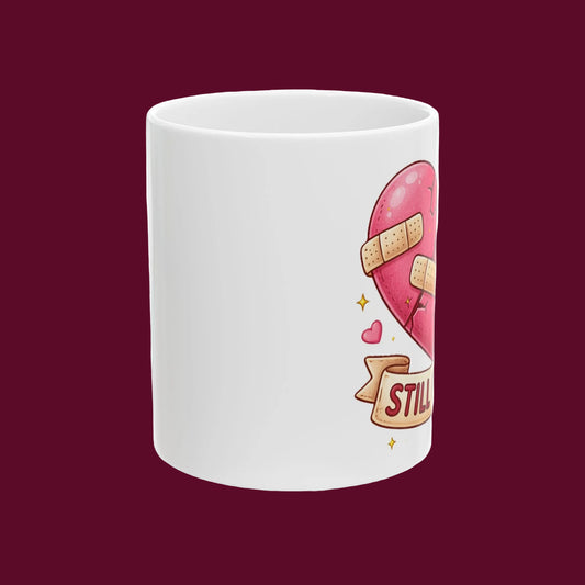 White mug with a heart design and 'STILL' text on a white background