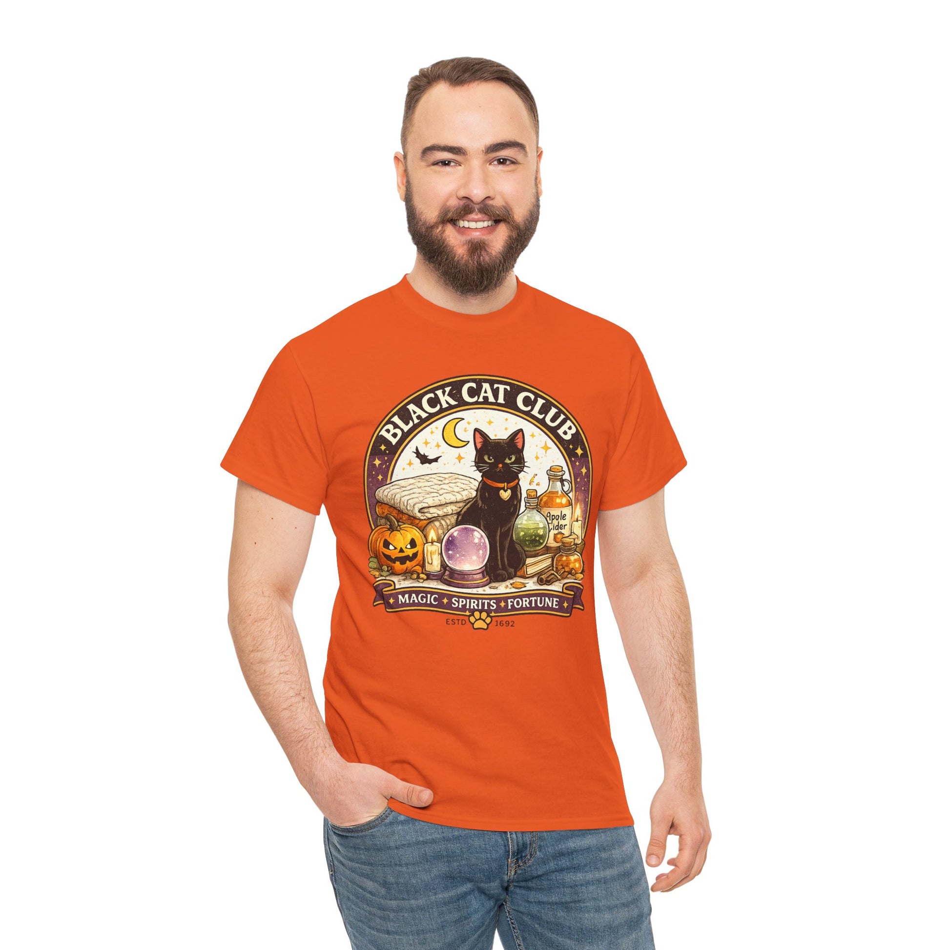 A man wearing a bright orange graphic t-shirt with a 'Black Cat Club' Halloween-themed print, paired with blue jeans, against a plain white background.