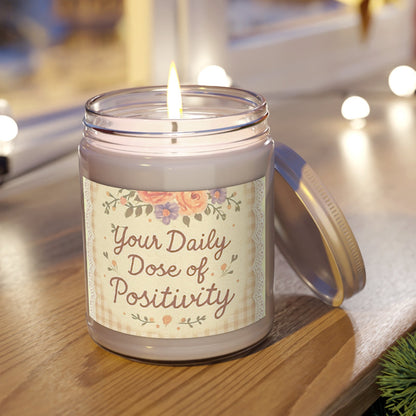 Candle in a jar with a label reading 'Your Daily Dose of Positivity' on a wooden surface.
