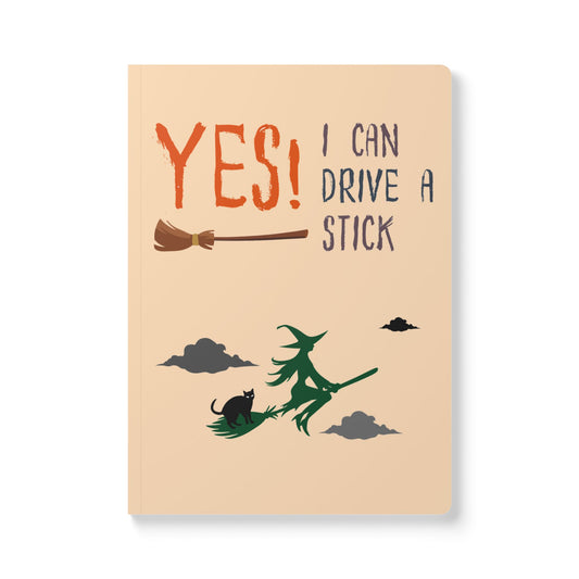 Notebook with a witch flying on a broomstick and text 'YES! I can drive a stick' on a beige background
