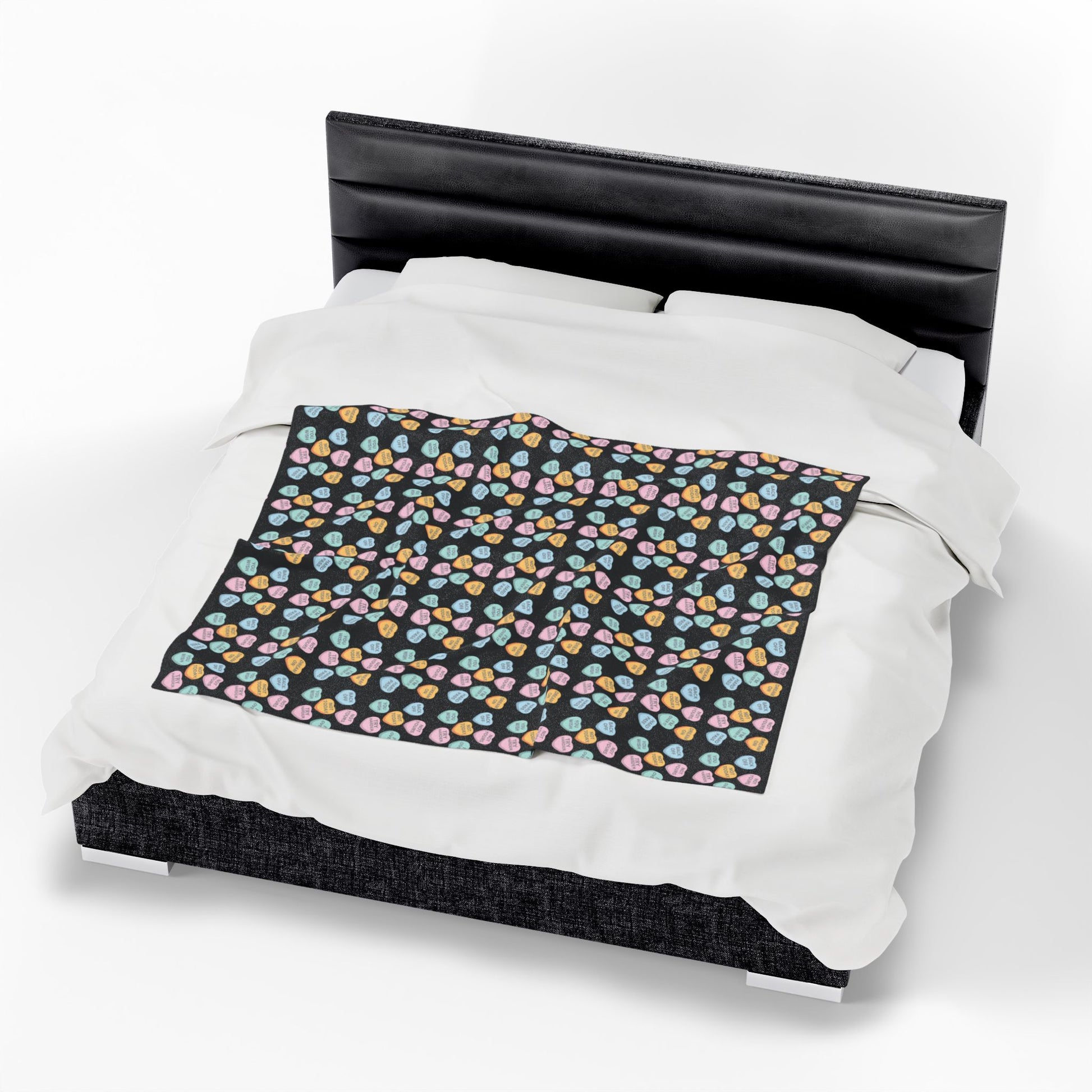 Bed with a black headboard and a colorful patterned blanket on white background