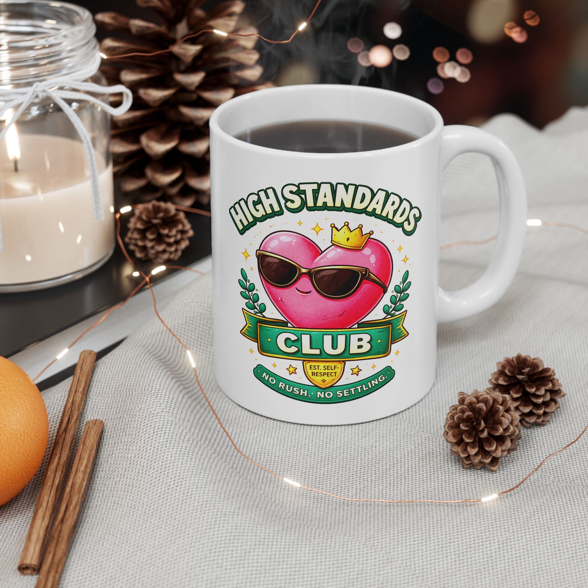 White mug with 'High Standards Club' design on a table with decorative items