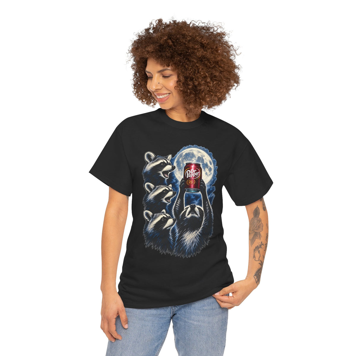 A woman with curly brown hair wearing a black graphic t-shirt and light wash blue jeans, standing against a plain white background.