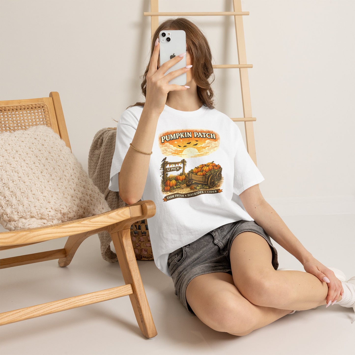 Person wearing a white t-shirt with a cat and butterfly graphic, sitting on the floor.