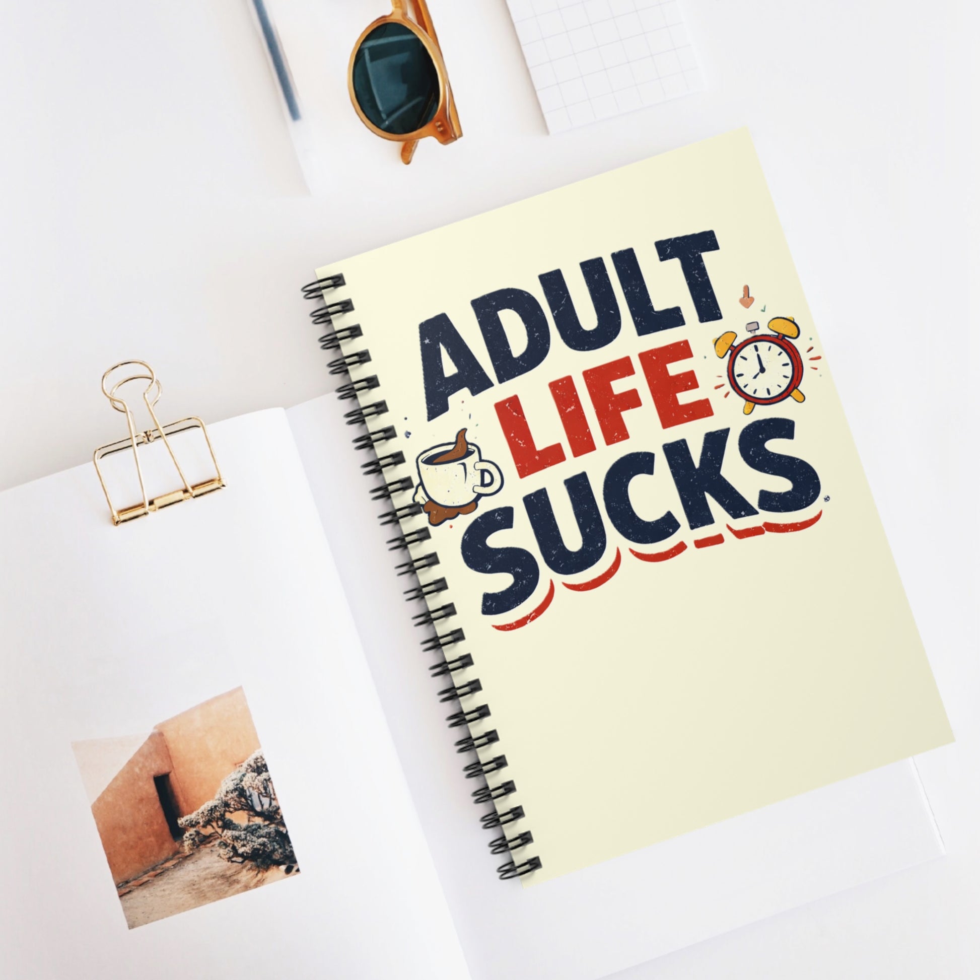 Notebook with 'Adult Life Sucks' cover on a white surface