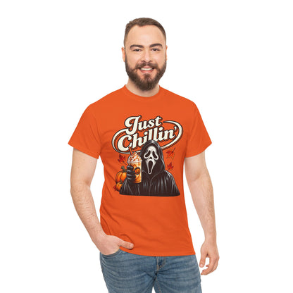A man wearing a bright orange graphic t-shirt with a Ghostface design and the text 'Just Chillin'', paired with blue jeans, against a plain white background.