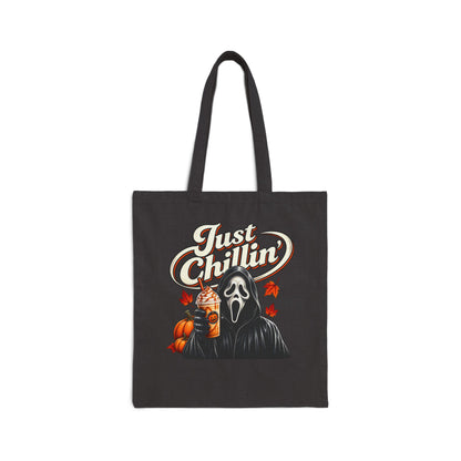A black canvas tote bag with long handles, featuring a graphic print of the Ghostface character holding an iced coffee with a pumpkin and the text 'Just Chillin'' in white and orange lettering.