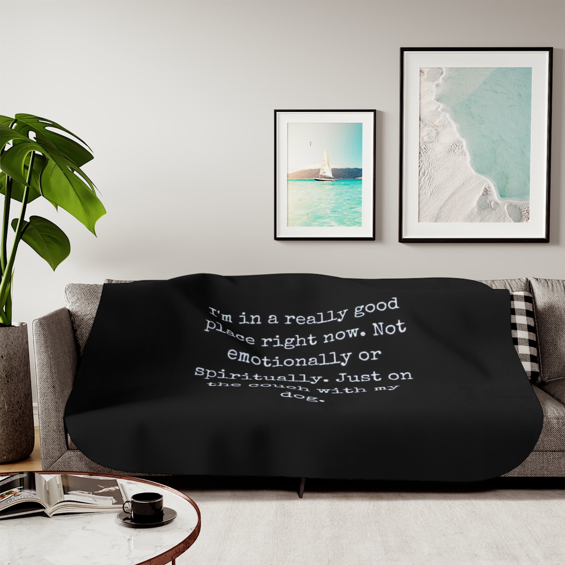 Black blanket with a quote on a gray couch in a living room setting.