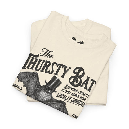 A folded white short-sleeve T-shirt with a large black graphic print reading 'The Thirsty Bat' and a bat illustration wearing a top hat, photographed on a clean white background.