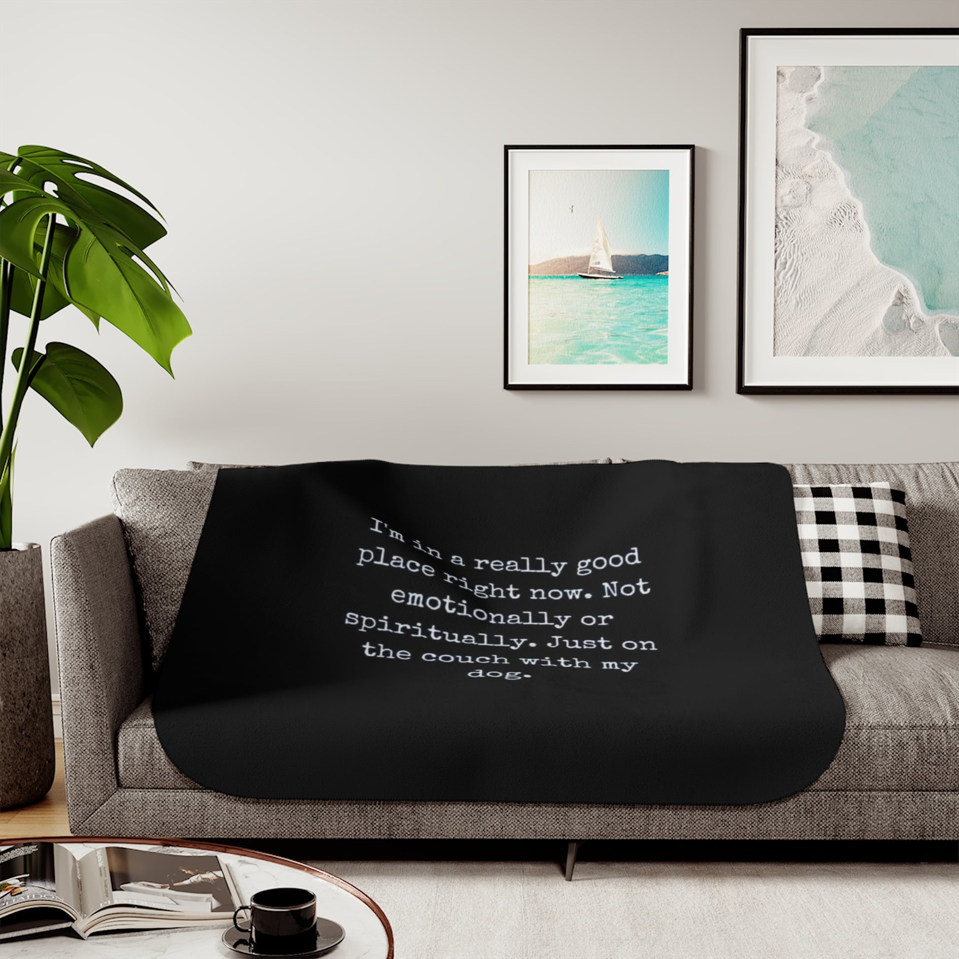 Black blanket with text on a gray couch in a living room setting