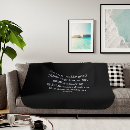 Black blanket with text on a gray couch in a living room setting