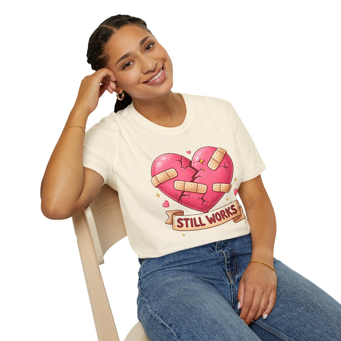 Person wearing a white t-shirt with a graphic design of a heart and text, sitting on a chair.