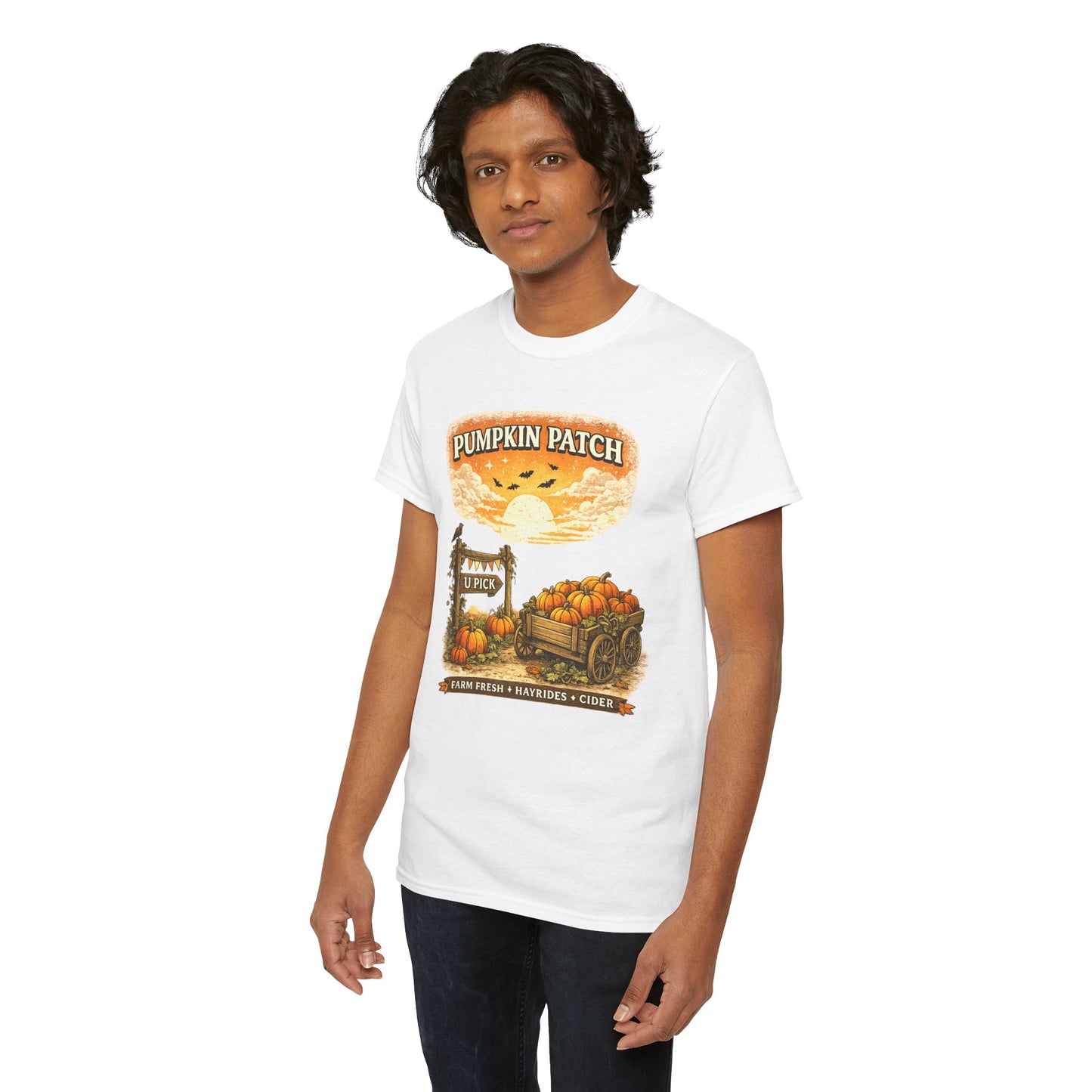 A man wearing a white short-sleeve graphic t-shirt with a 'Pumpkin Patch' autumn harvest design on the front, paired with dark jeans, set against a plain white background.