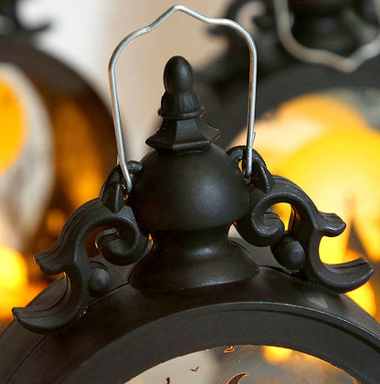 Decorative black lantern with intricate details against a warm, blurred background