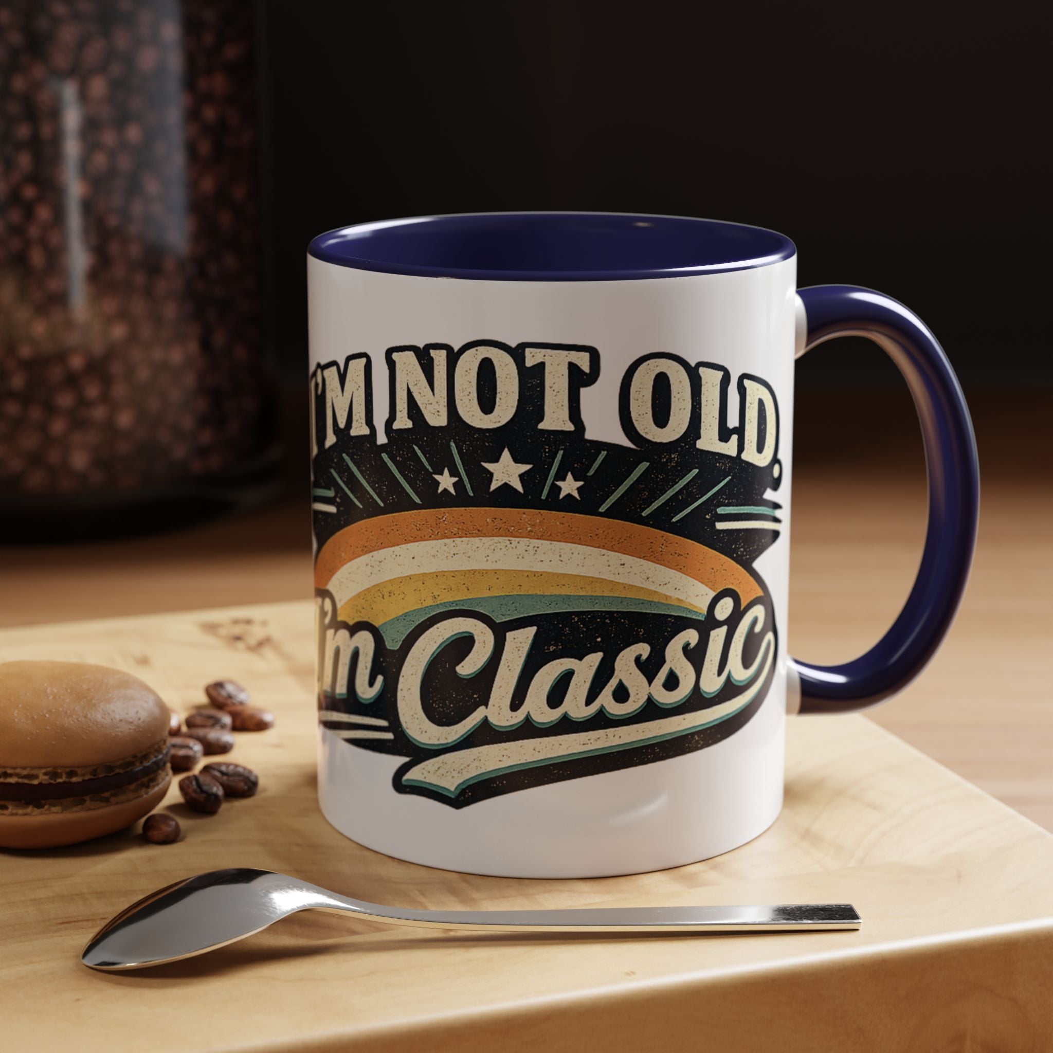 Mug with 'I'm not old, I'm classic' text on a wooden surface with coffee beans and a spoon.