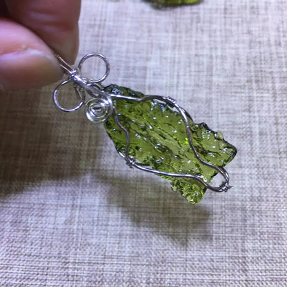 Discover the unique beauty of natural green moldavite with our stunning necklace. Created by the natural force of meteorite impact, this necklace boasts a one-of-a-kind natural shape and impressive dark green hue. Add a touch of rare elegance to your jewelry collection with this incredible piece.