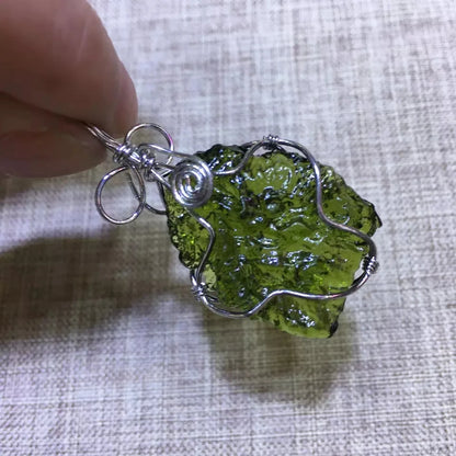 Discover the unique beauty of natural green moldavite with our stunning necklace. Created by the natural force of meteorite impact, this necklace boasts a one-of-a-kind natural shape and impressive dark green hue. Add a touch of rare elegance to your jewelry collection with this incredible piece.