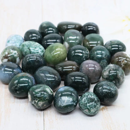 Collection of green and gray marbled stones on a light wooden surface