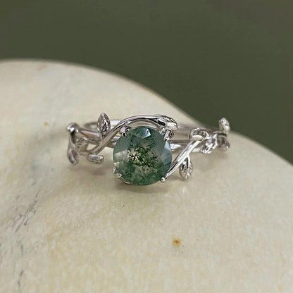Silver ring with a green gemstone on a stone surface