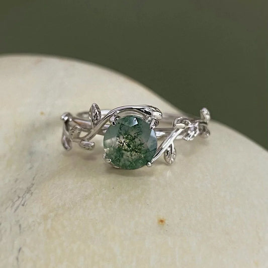 Silver ring with a green gemstone on a stone surface
