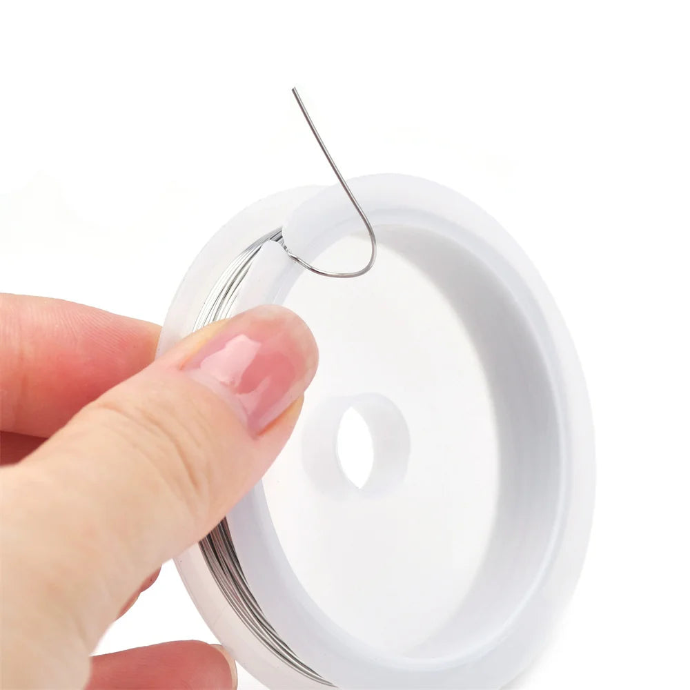 Hand holding a spool of thread with a needle above it on a white background