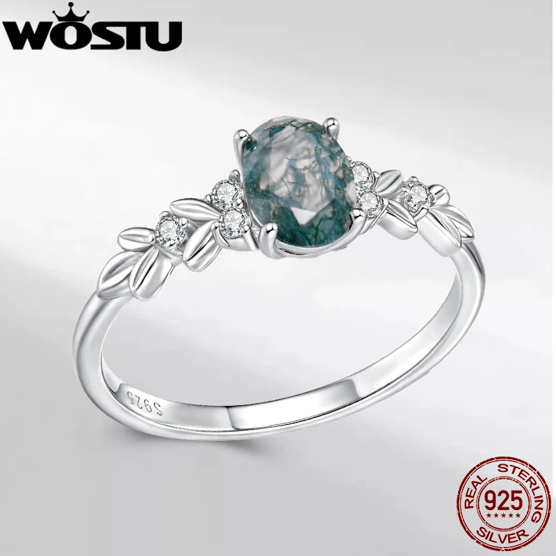 Silver ring with a green gemstone and 'WOSTU' branding on a white background