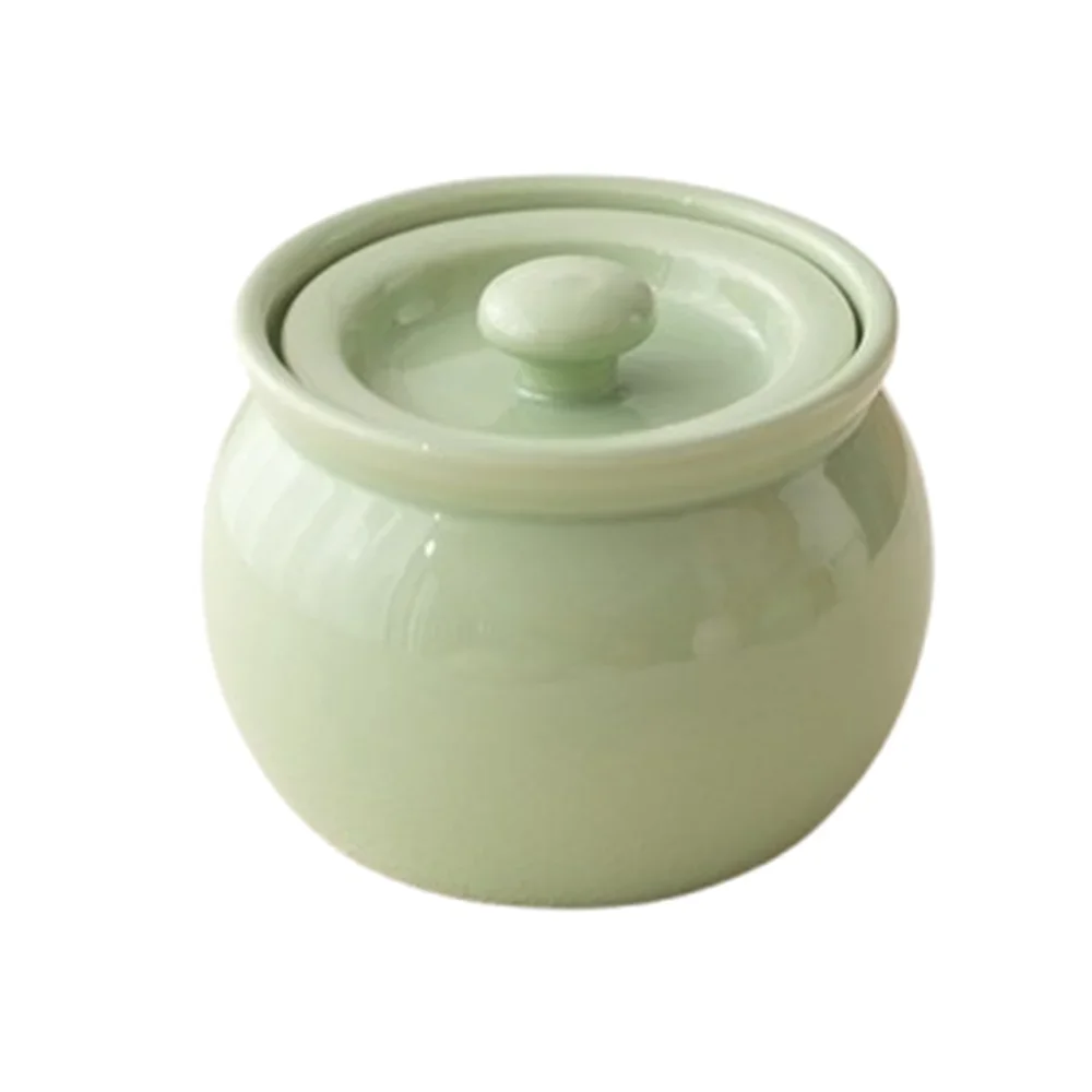 Green ceramic jar with a lid on a white background