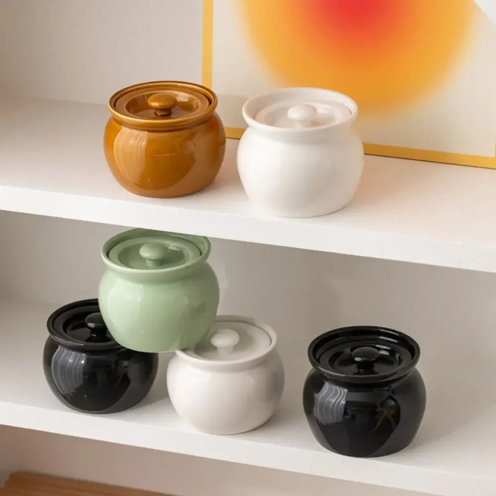 Set of ceramic pots with lids on a white shelf