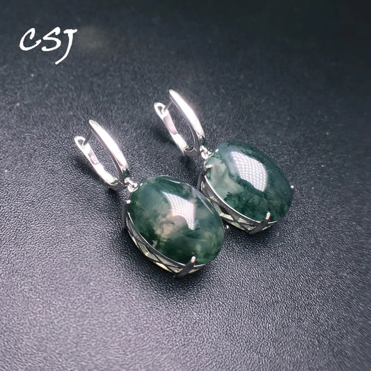 Green stone earrings with silver settings on a dark background