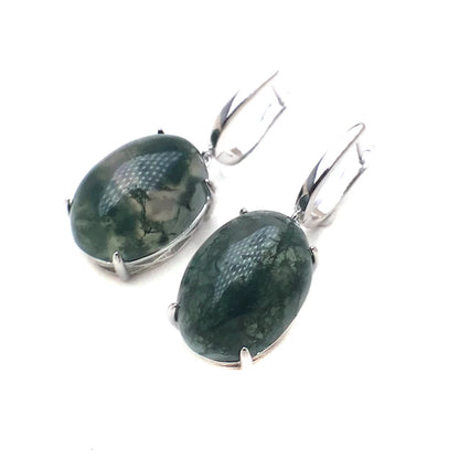 Pair of earrings with green stone and silver setting on a white background
