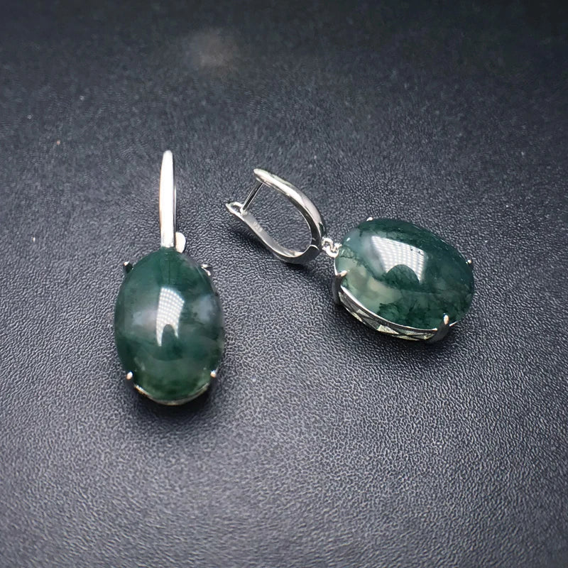 Pair of green gemstone earrings on a dark surface
