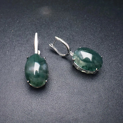 Pair of green gemstone earrings on a dark surface
