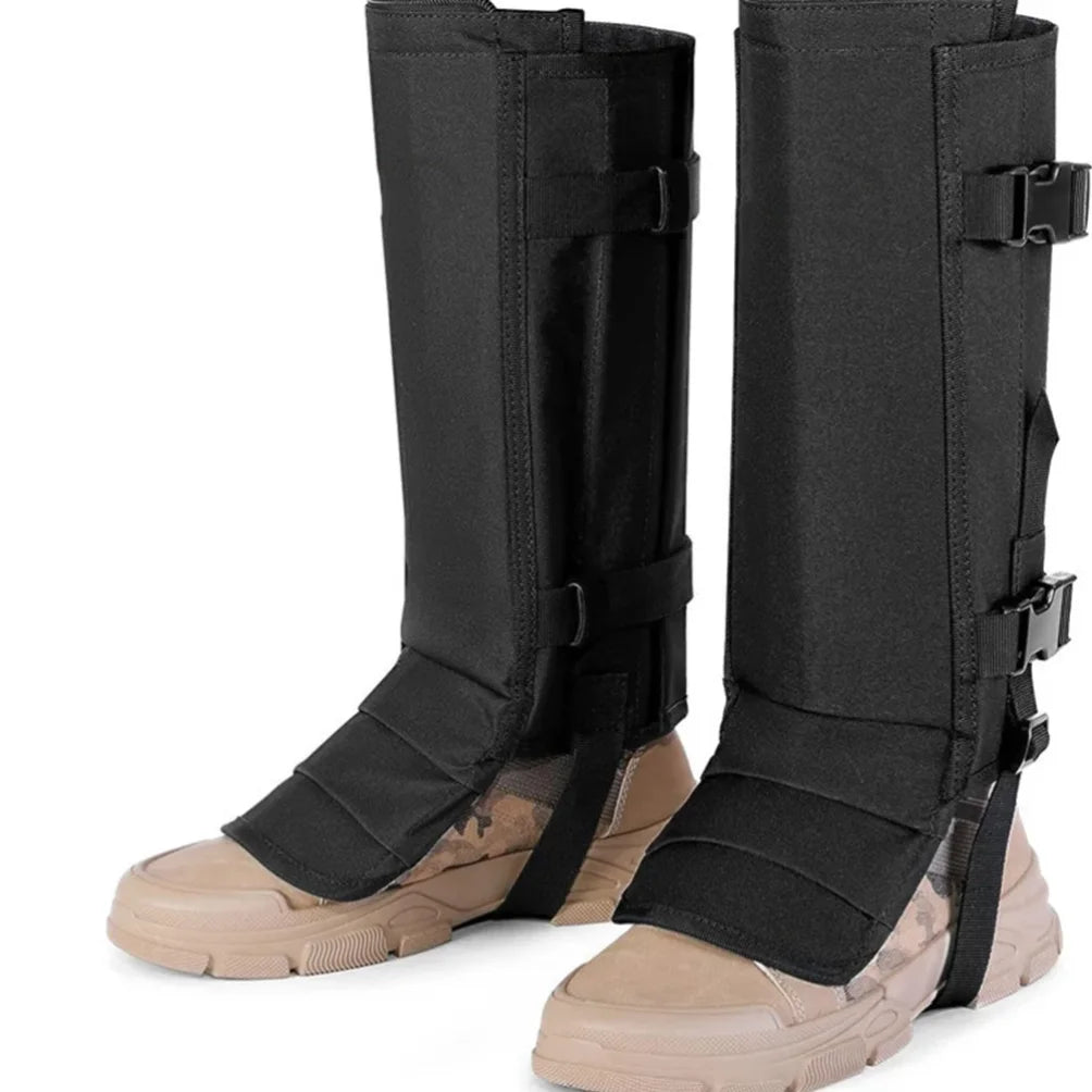 A pair of black tactical leg guards with adjustable straps and buckles, shown worn over tan combat boots on a white background.