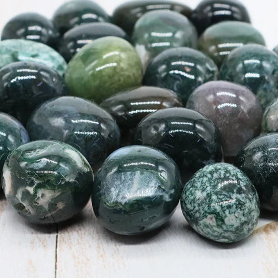 Collection of green and gray marbled stones on a light wooden surface