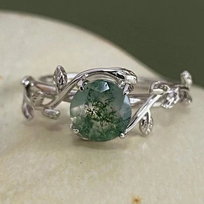Silver ring with a green gemstone on a stone surface