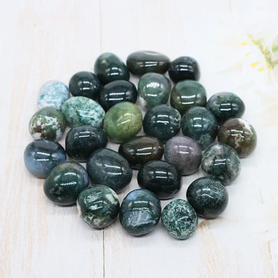 Collection of green and gray marbled stones on a light wooden surface